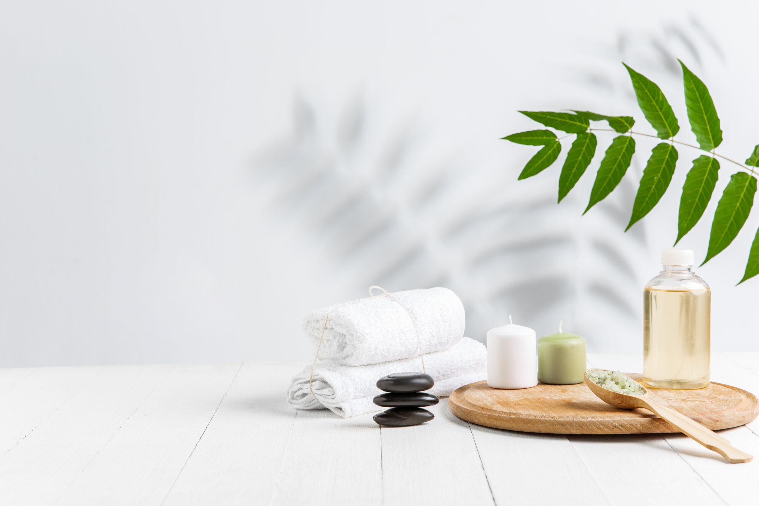 Beautiful spa composition on massage table in wellness center, copyspace. Accessories for relaxing treatments and personal care. Towels, oils, serum, sea salts and scrubs. Decorative candles.